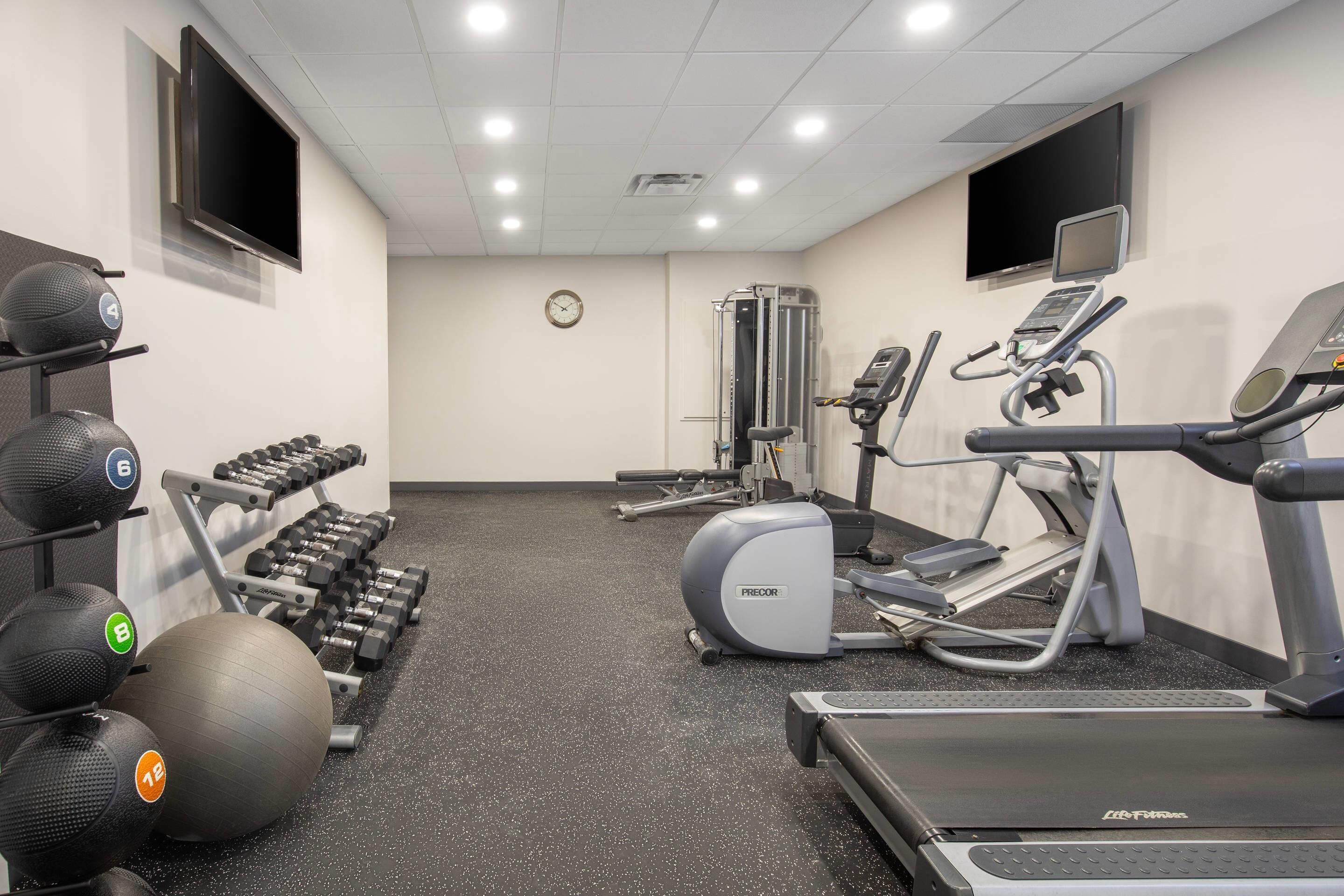 Une salle de sport équipée de tapis de course, de vélos elliptiques et de poids libres.