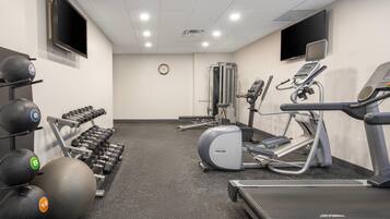 Une salle de sport équipée de tapis de course, de vélos elliptiques et de poids libres.
