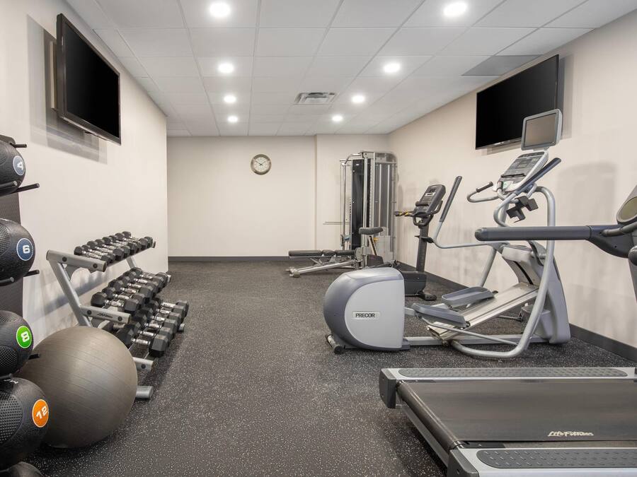 Une salle de sport équipée de tapis de course, de vélos elliptiques et de poids libres.