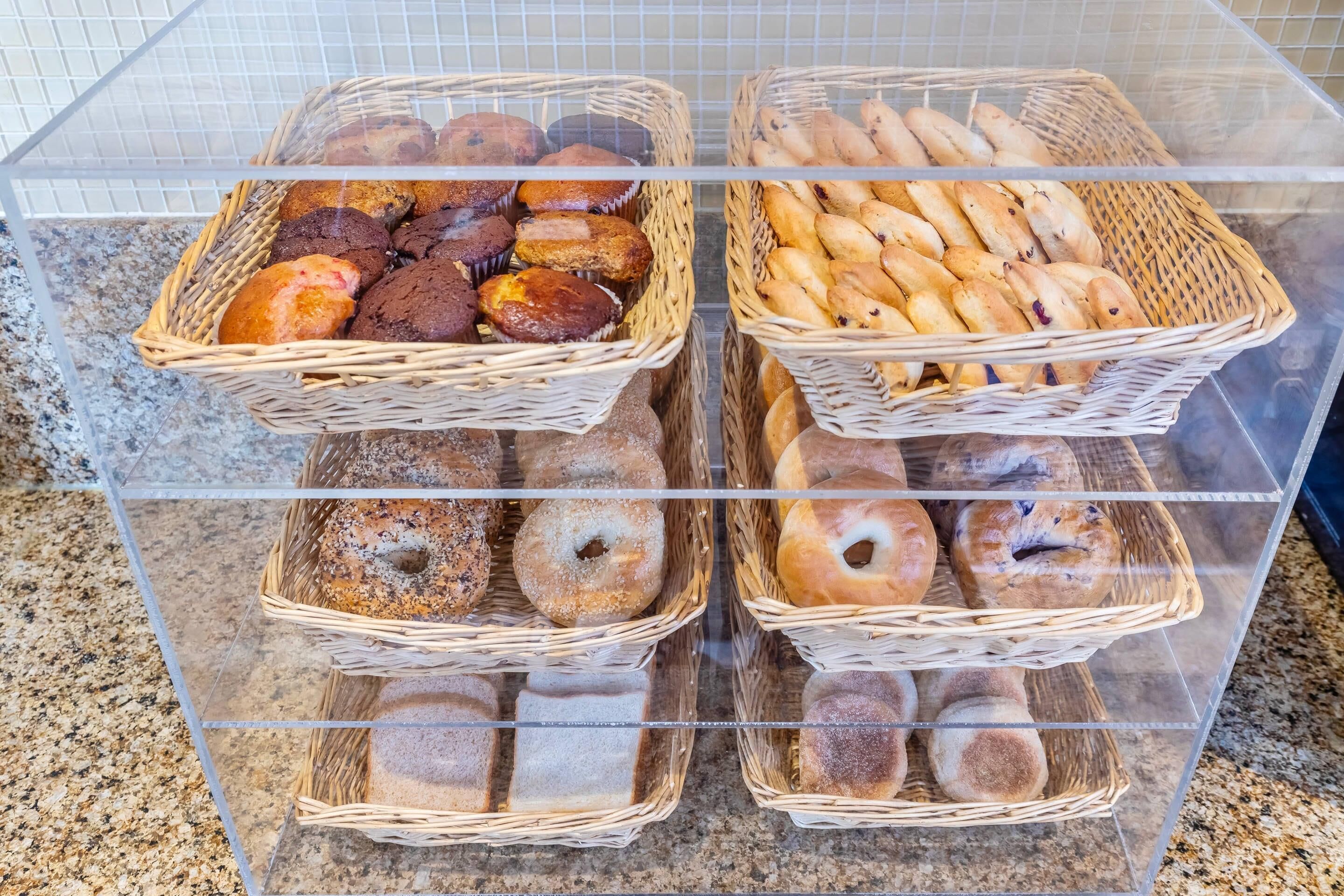 Een vitrine met diverse gebakken producten, waaronder muffins, bagels en gebak.