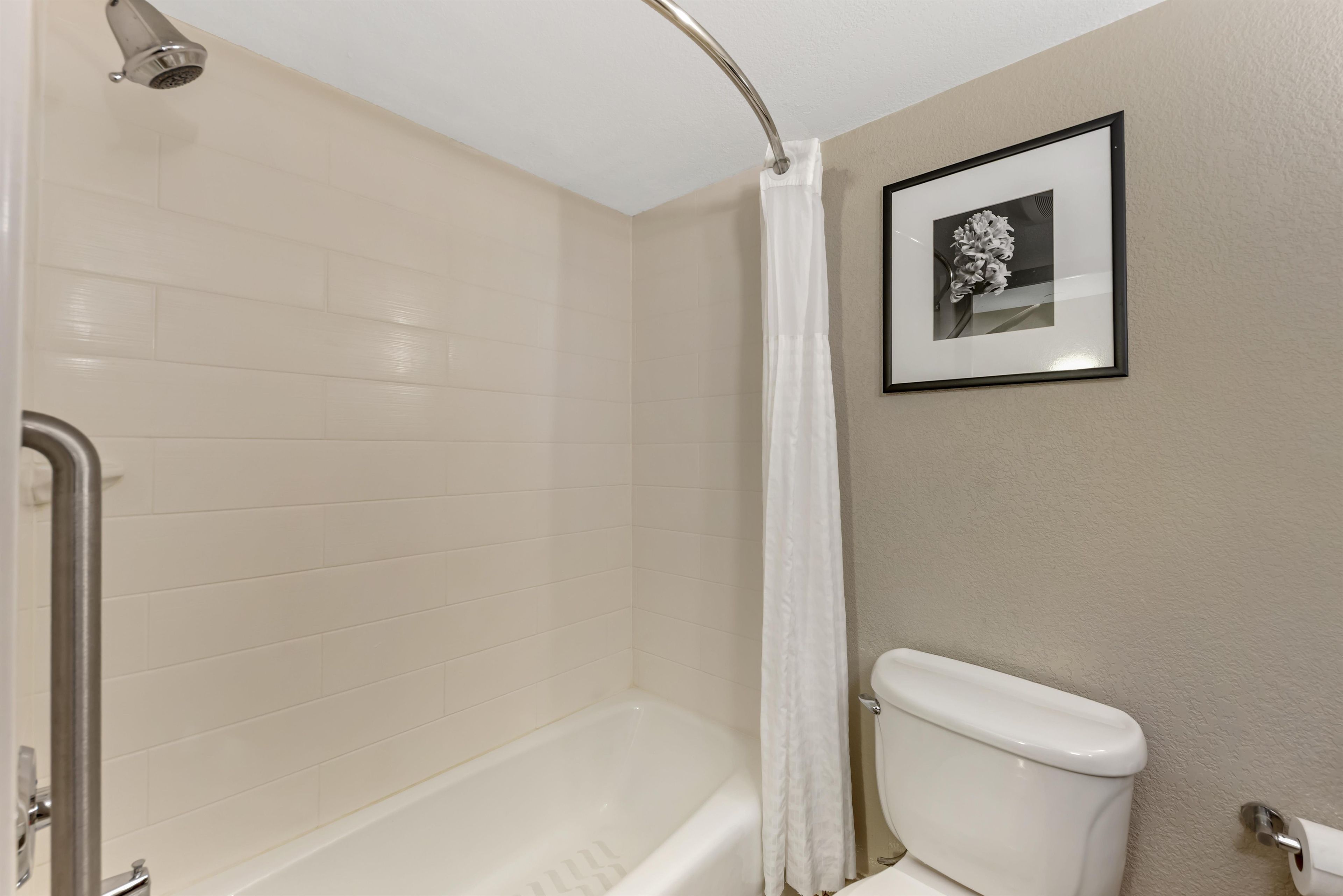 A bathroom with a bathtub, toilet, and a shower curtain.