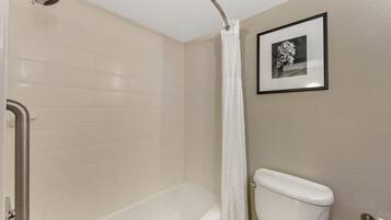 A bathroom with a bathtub, toilet, and a shower curtain.