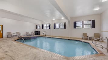 Una piscina con hidromasaje, rodeada de sillas y un vestuario.