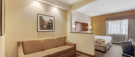 Habitación de hotel con sofá, cama, escritorio y ventilador de techo.