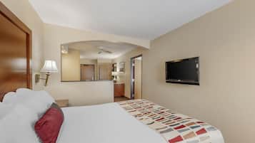 Une chambre d’hôtel avec un lit, un téléviseur fixé au mur, un ventilateur de plafond et un miroir qui reflète la pièce.