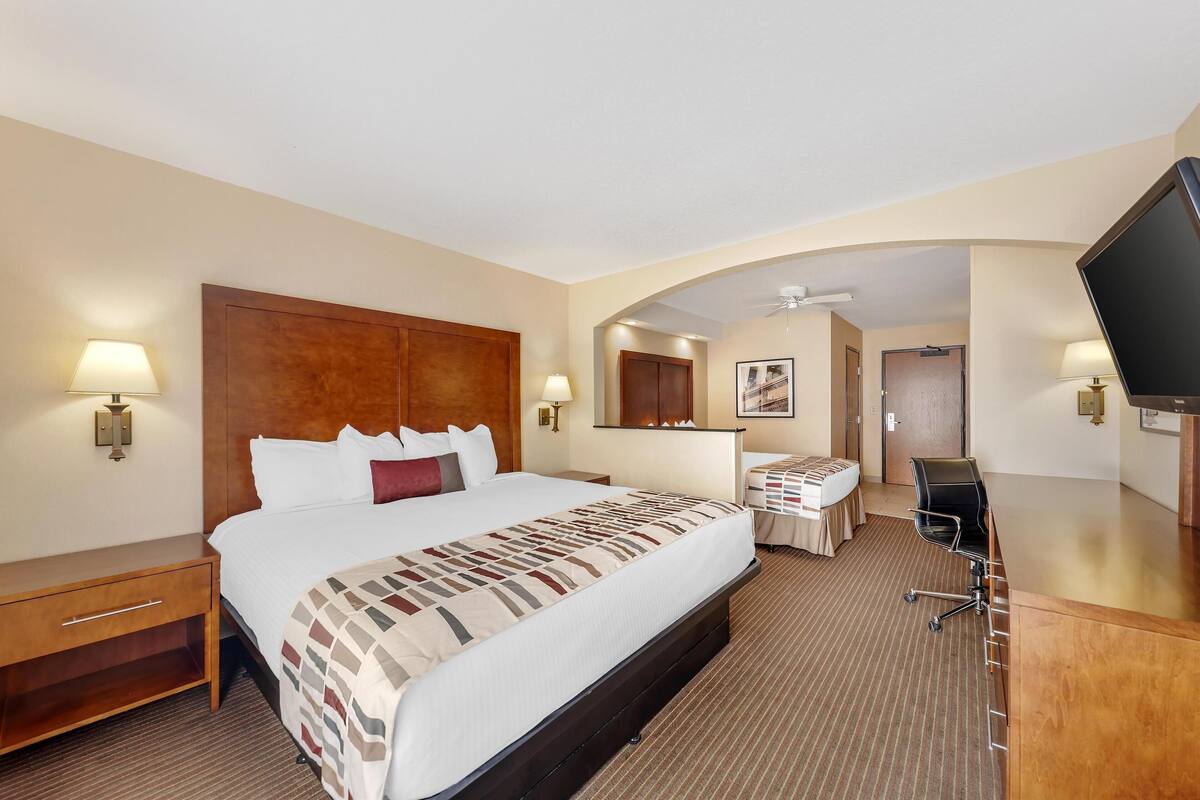A hotel room with a large bed, a desk, a television, and a bathroom door.