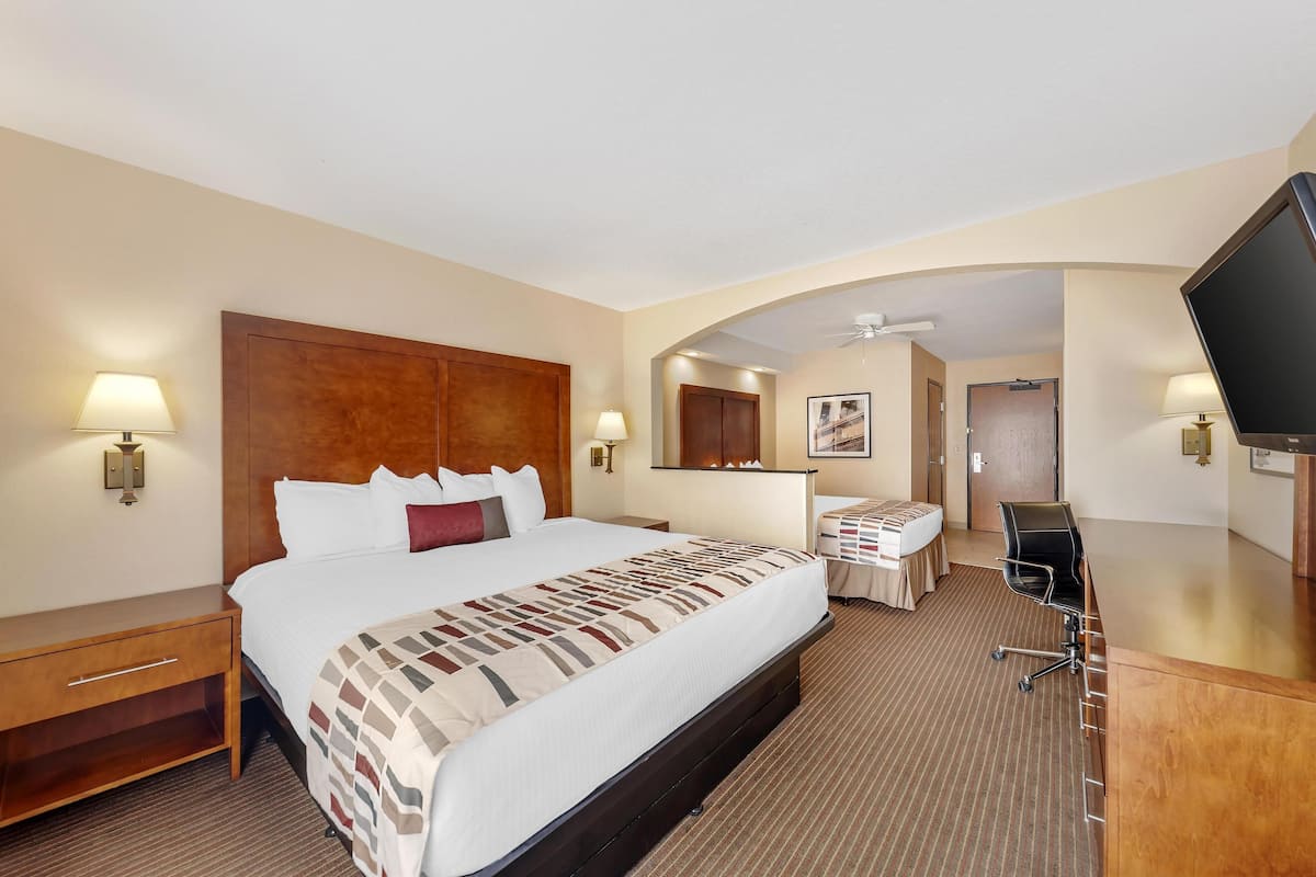 A hotel room with a large bed, a desk, a television, and a bathroom door.