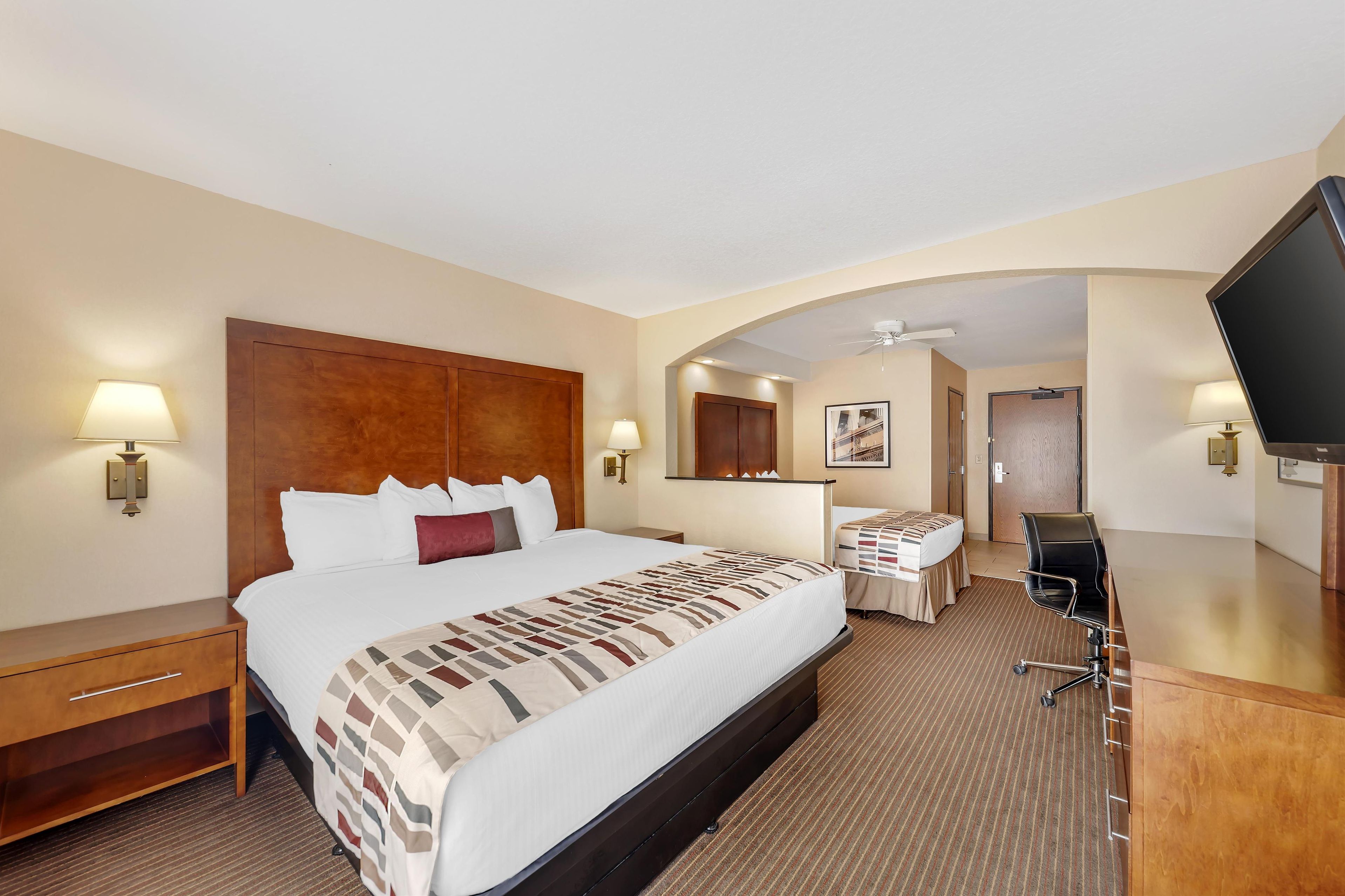 A hotel room with a large bed, a desk, a television, and a bathroom door.