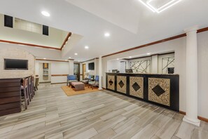 A spacious lobby with a reception desk, seating area, and a stone fireplace. - Best Western Alamo Suites (San Antonio)