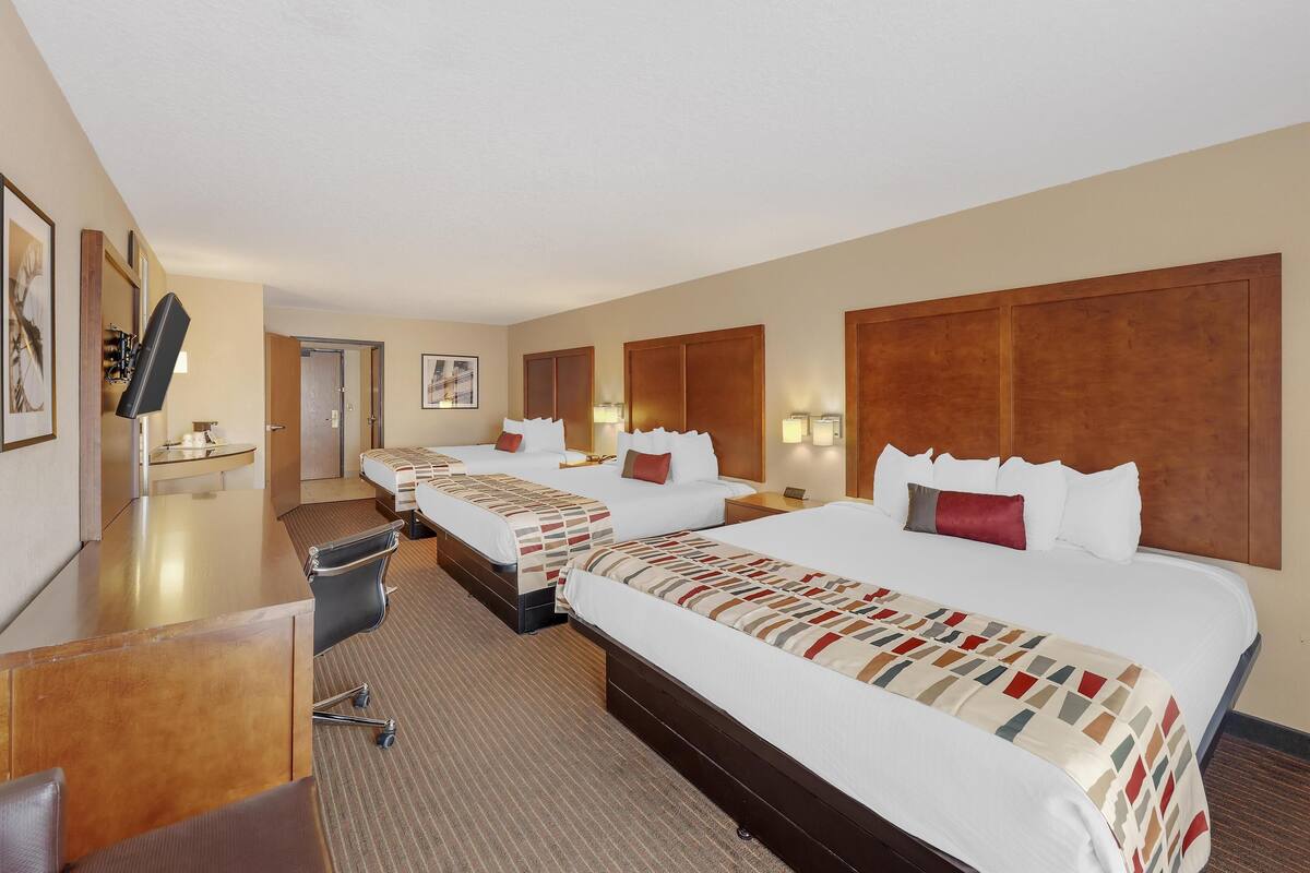 A hotel room with a large bed, a desk, and a chair.