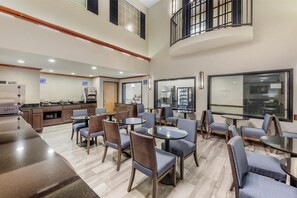 A spacious indoor area with multiple seating arrangements, a kitchen area, and a view through a large window. - Best Western Alamo Suites (San Antonio)