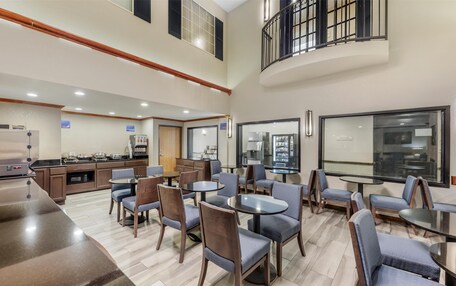 A spacious indoor area with multiple seating arrangements, a kitchen area, and a view through a large window.
