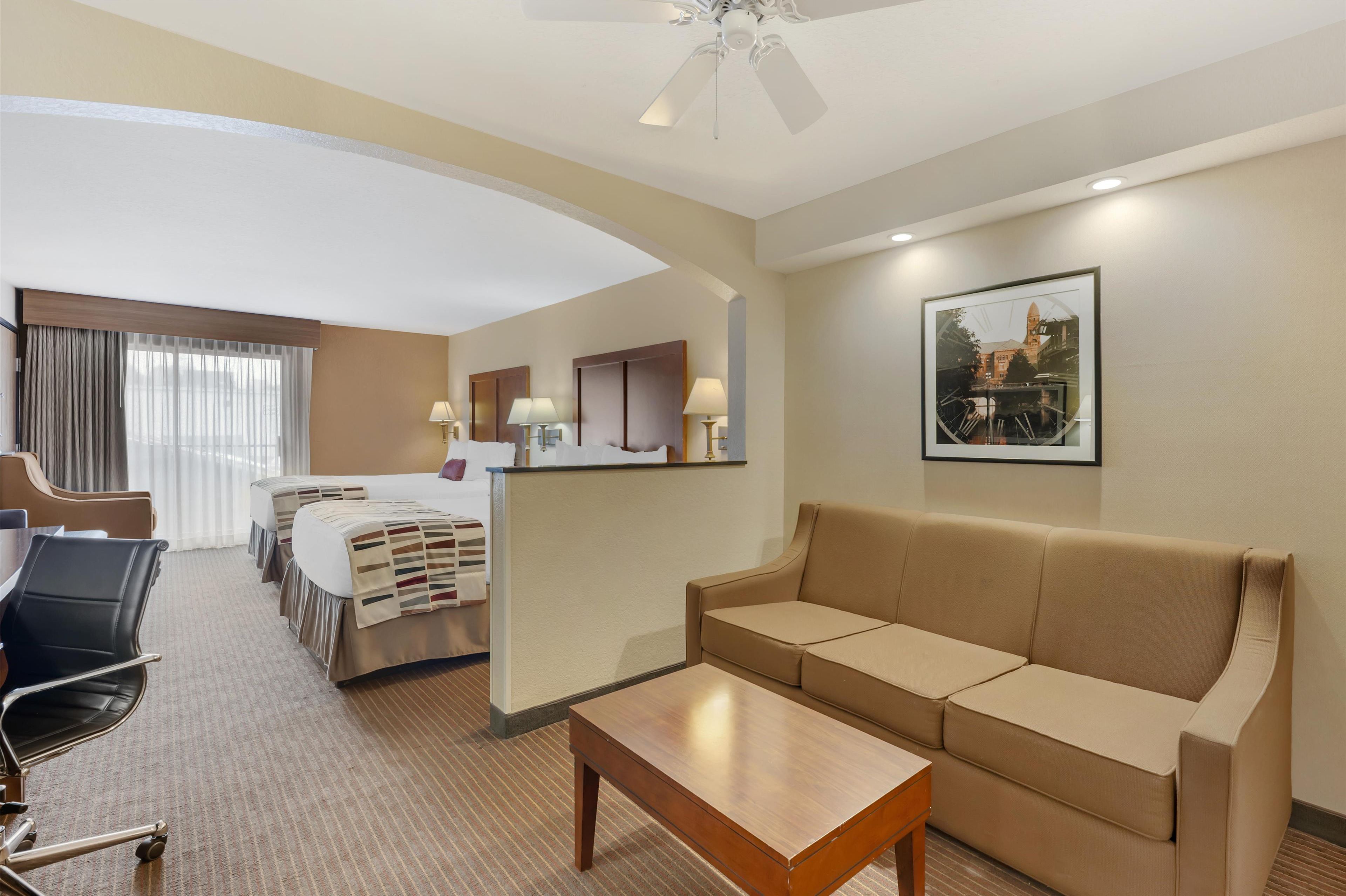 A hotel room with a bed, a sofa, a desk, and a chair.