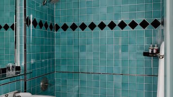 Casa de banho com azulejos verde-água, uma moldura em padrão de losangos preto e branco, uma pia branca e área de duche.