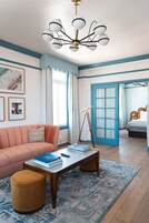Una habitación con sofá, mesa de centro, telescopio, cama y puerta azul.