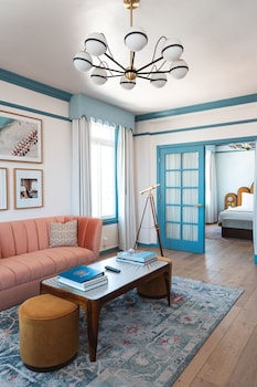 A living room with a sofa, armchair, coffee table, framed artwork, and a bookshelf. at The Georgian, in The Unbound Collection by Hyatt