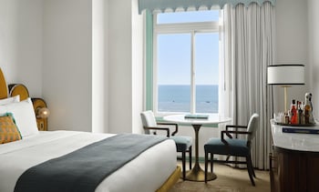 A room with a sofa, a coffee table, a telescope, a bed, and a blue door. at The Georgian, in The Unbound Collection by Hyatt
