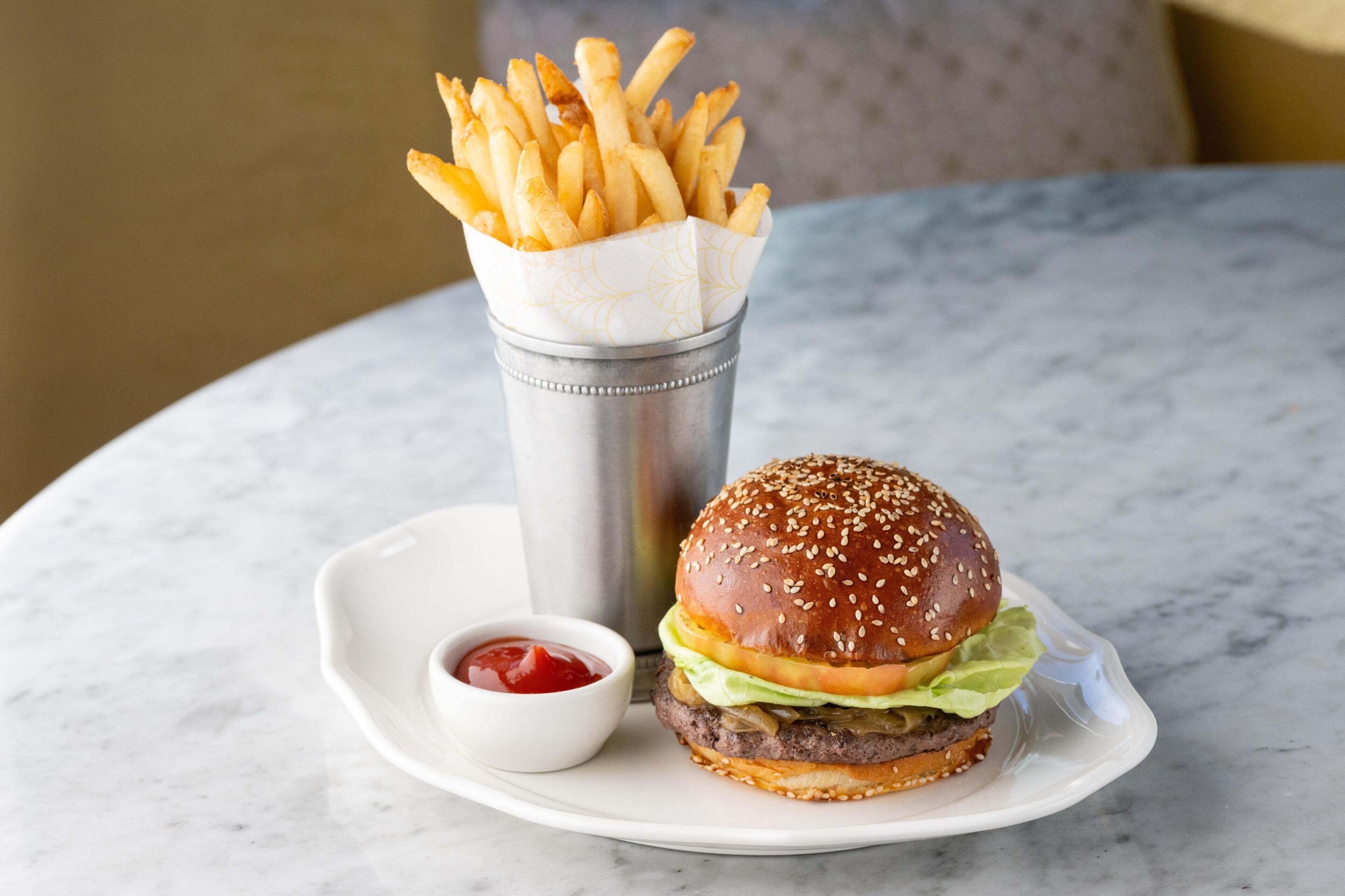 Een hamburger en frietjes op een bord met een ketchupbeker.