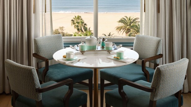 A dining area with a table set for four, overlooking a beach. - The Georgian, in The Unbound Collection by Hyatt (Santa Monica)