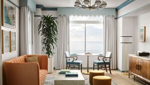A modern living room with a sofa, ottomans, a coffee table, and a view of the sea. - The Georgian, in The Unbound Collection by Hyatt (Santa Monica)