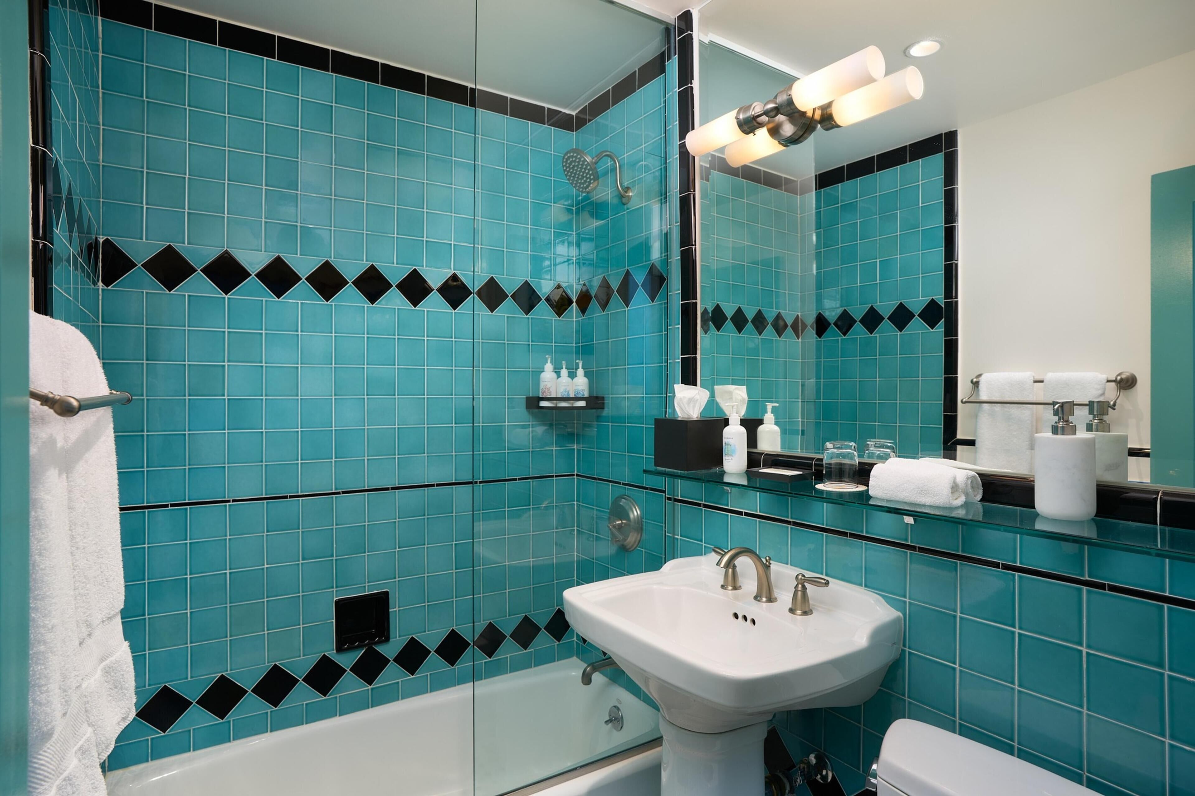A bathroom with a white sink, a glass-enclosed shower, and a mirror with a light fixture.