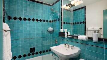 Un baño con un lavamanos blanco, una ducha con cerramiento de vidrio y un espejo con luz.