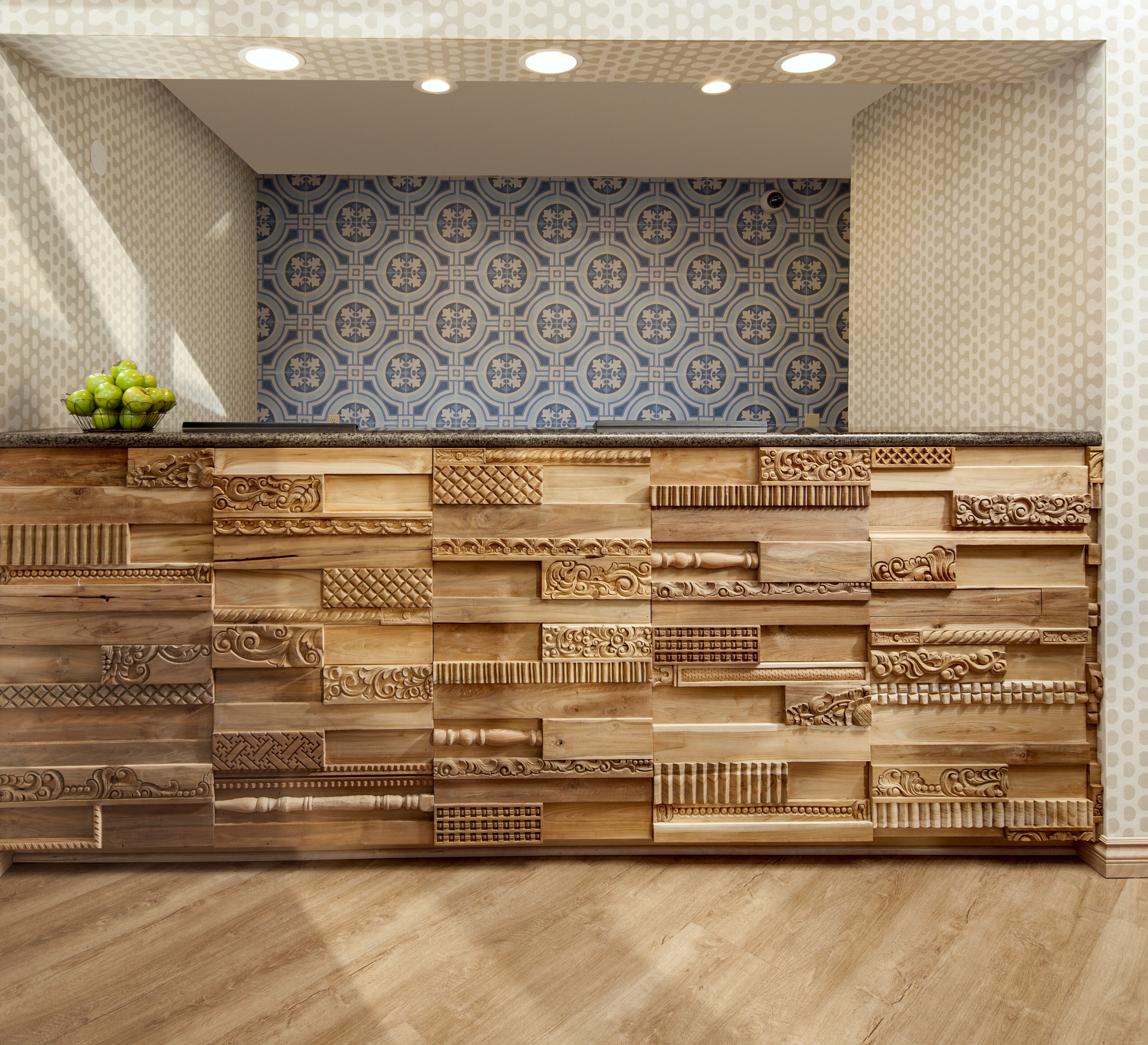 A reception desk with intricate wood carvings and a patterned tile backsplash.