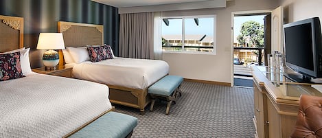 Quarto de hotel com duas camas, televisão, escrivaninha e varanda com vista.