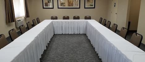 A conference room with a long table, chairs, and framed artwork on the wall.