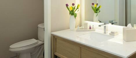 A modern bathroom with a toilet, a sink, a mirror, and a towel rack.