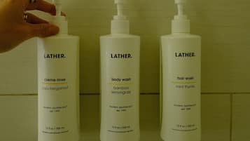 Three Latherm toiletries bottles against a tiled wall.