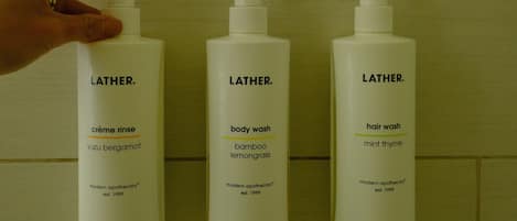 Three Latherm toiletries bottles against a tiled wall.