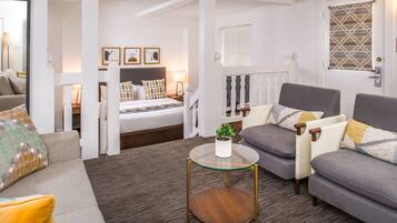 Una sala de estar moderna con sofá, sillón y una mesa de centro de vidrio.