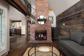 A living room with a fireplace, a sofa, a dining area, and a staircase. - Wine Valley Inn (Solvang)