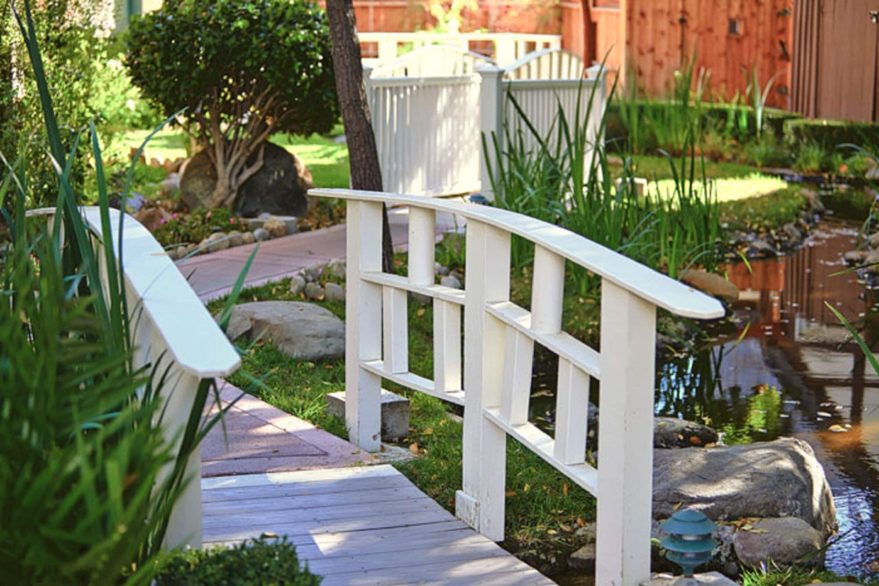 A wooden bridge over a small stream in a garden setting.