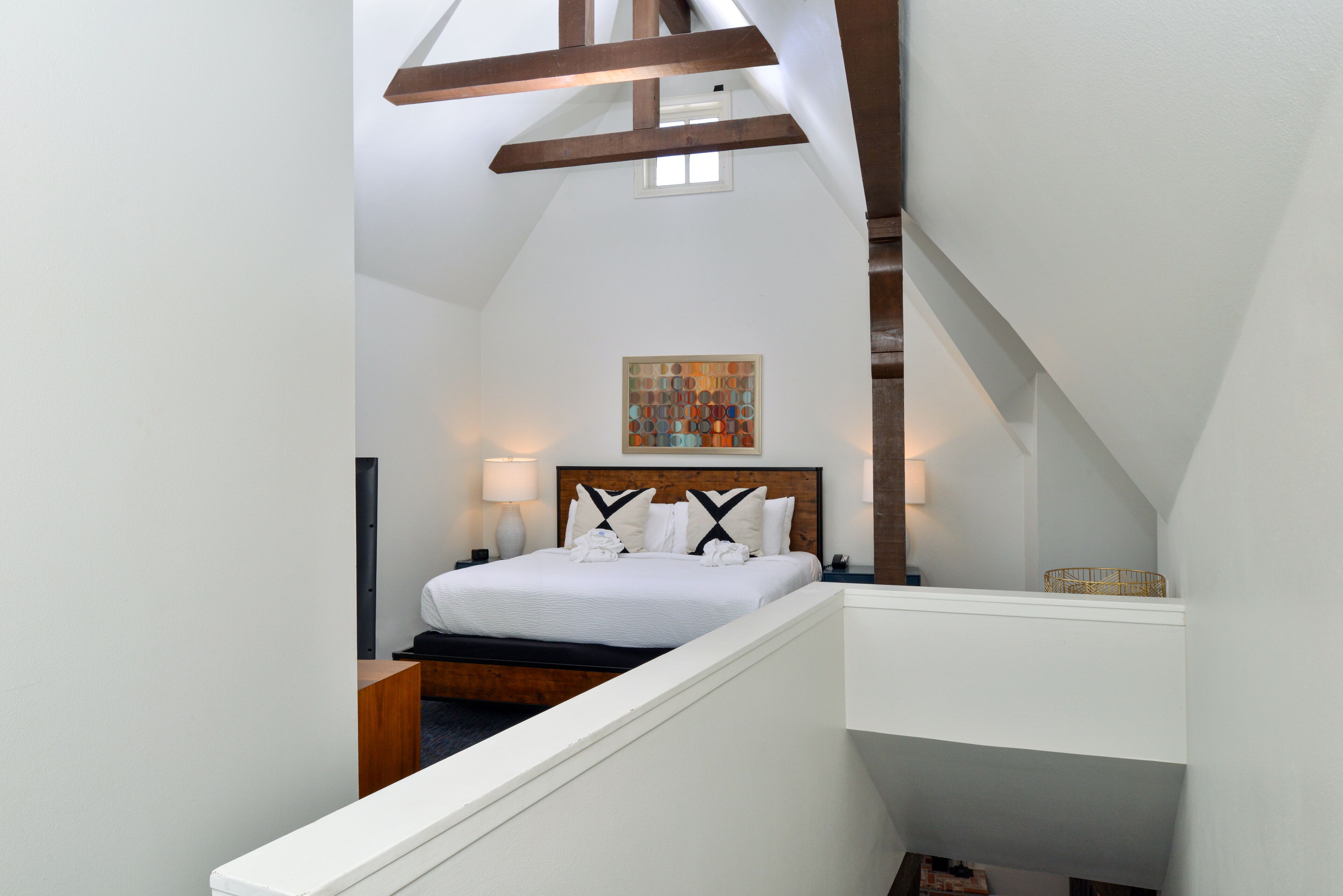A bedroom with a bed, a nightstand, a lamp, and a painting on the wall.