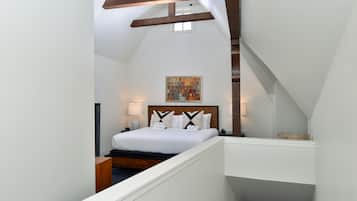 A bedroom with a bed, a nightstand, a lamp, and a painting on the wall.