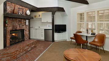 Una cocina moderna con armarios blancos, una chimenea de ladrillo y un comedor con una mesa redonda y dos sillas.