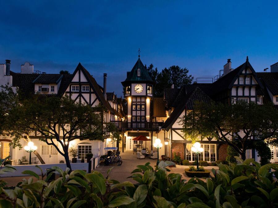 A traditional Tudor-style building with a clock tower, a covered patio area, and a well-maintained garden.