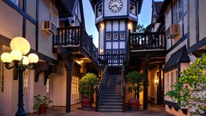 A traditional European-style building with a clock tower, a staircase leading to the upper floor, and potted plants. - Wine Valley Inn (Solvang)