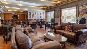 A spacious living area with a large brown leather sofa, a coffee table, and a dining area with wooden chairs and a kitchen in the background. - Best Western Plus Thousand Oaks Inn (Thousand Oaks)
