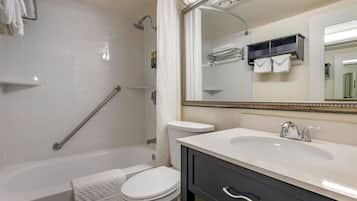 A modern bathroom with a bathtub, toilet, and vanity with a sink and mirror.