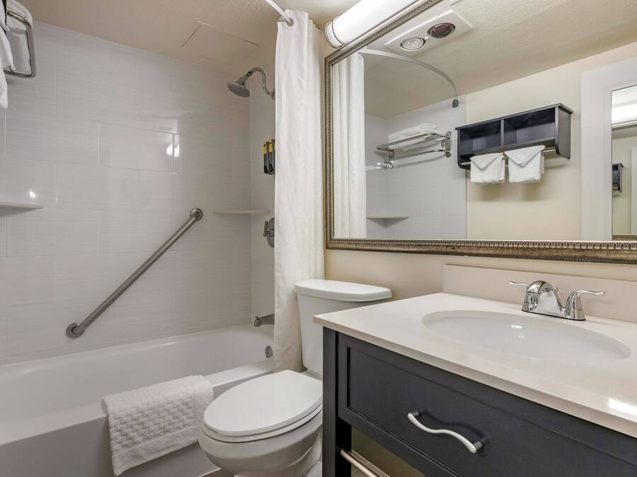 A modern bathroom with a bathtub, toilet, and vanity with a sink and mirror.