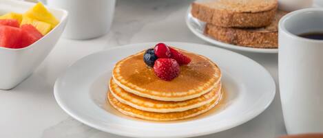A breakfast setting with pancakes, waffles, and a sandwich.