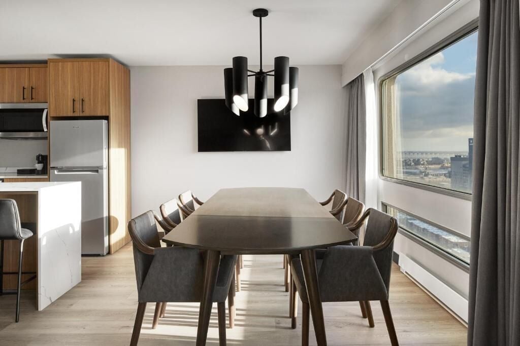 Een moderne keuken met een eethoek, grote ramen en uitzicht over de stad.