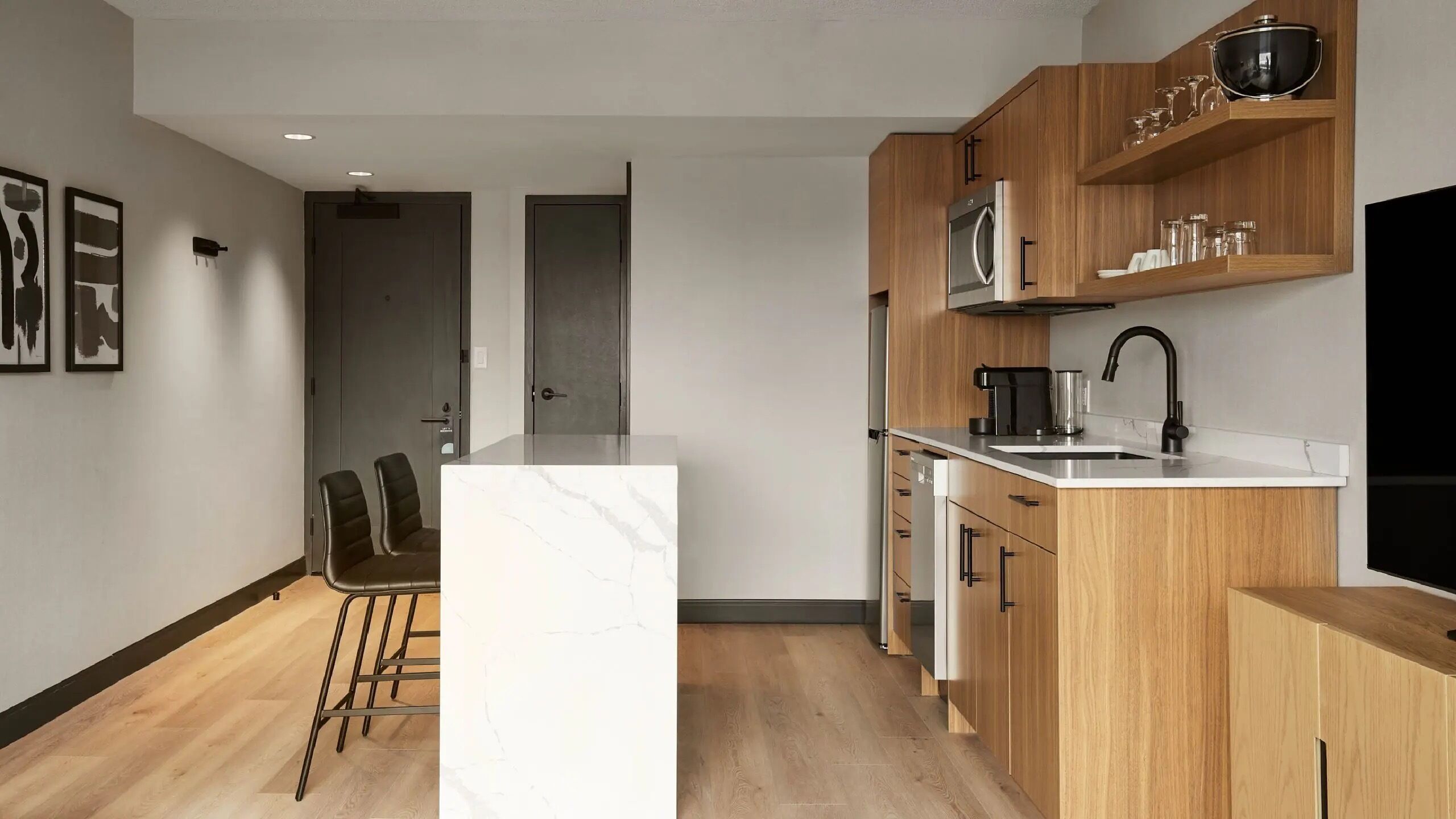 Een moderne keuken met een centraal eiland, houten kastjes en een inbouwoven.