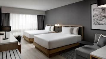 Une chambre d’hôtel avec deux lits, un bureau, une chaise, un canapé et une lampe.