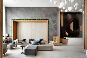 A modern lobby with seating areas, a reception desk, and a geometric wall design.