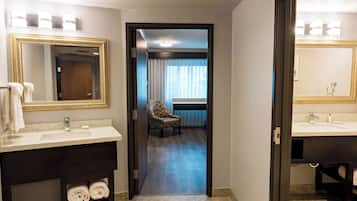 A hotel bathroom with two sinks, a mirror with a gold frame, and a chair in the background.