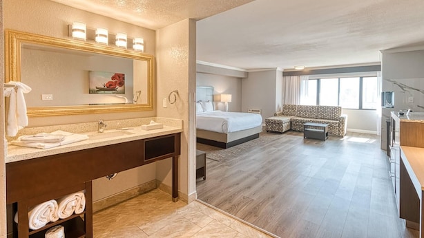 A hotel room with a bathroom, a bed, a sofa, and a desk.